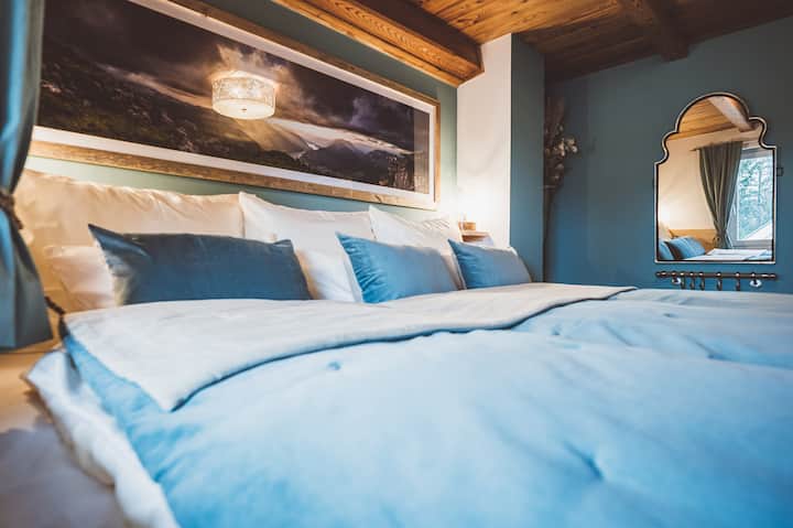 ห้องนอนสบายๆ พร้อมเตียงขนาดใหญ่พิเศษสำหรับครอบครัว (กว้างประมาณ 250 ซม.) การตกแต่งทันสมัย บรรยากาศสว่างและกระจก เหมาะสำหรับครอบครัวหรือผู้เข้าพัก มีพื้นที่กว้างขวางและนอนหลับสบาย – กว้างกว่าเตียงคิงไซส์!