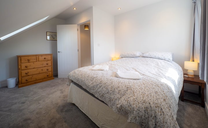 ห้องนอนขนาดใหญ่ชั้นบนพร้อมเตียงขนาดซูเปอร์คิงไซส์และหน้าต่างที่หันหน้าไปทางทิศใต้