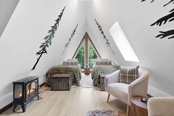 Acogedor loft con forma de A, camas individuales, vistas al bosque y una cálida estufa de leña