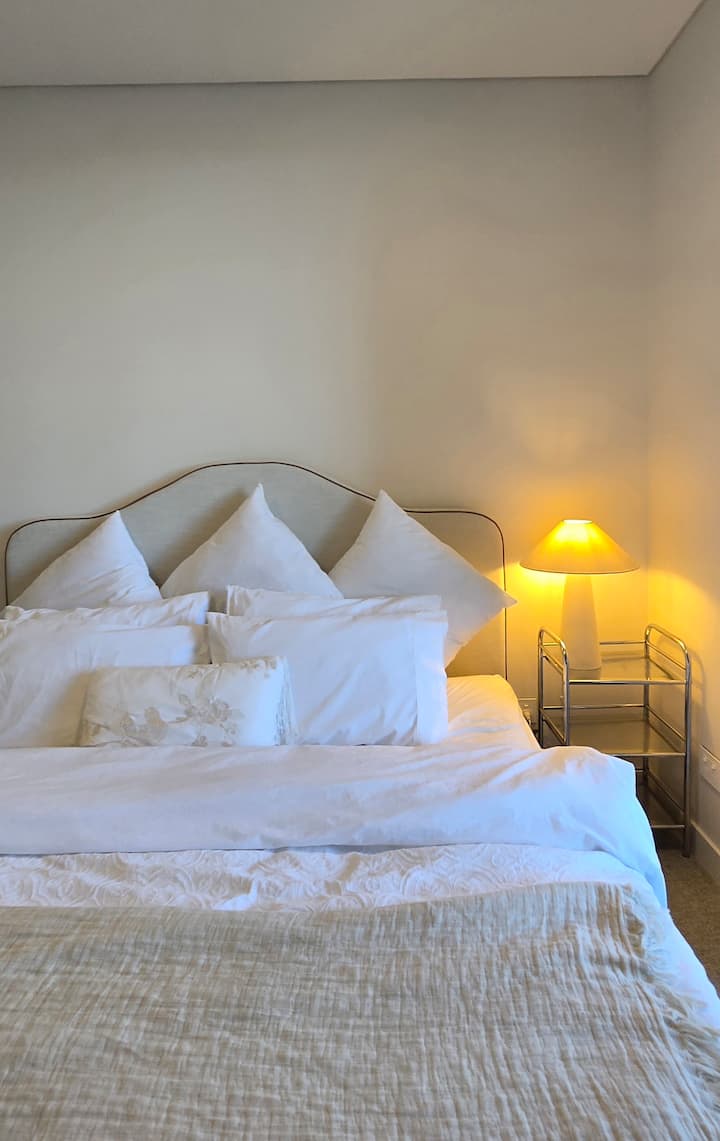 מיטת קינג סייז מפוארת בחדר האמבטיה הראשי עם גישה ישירה לחצר.