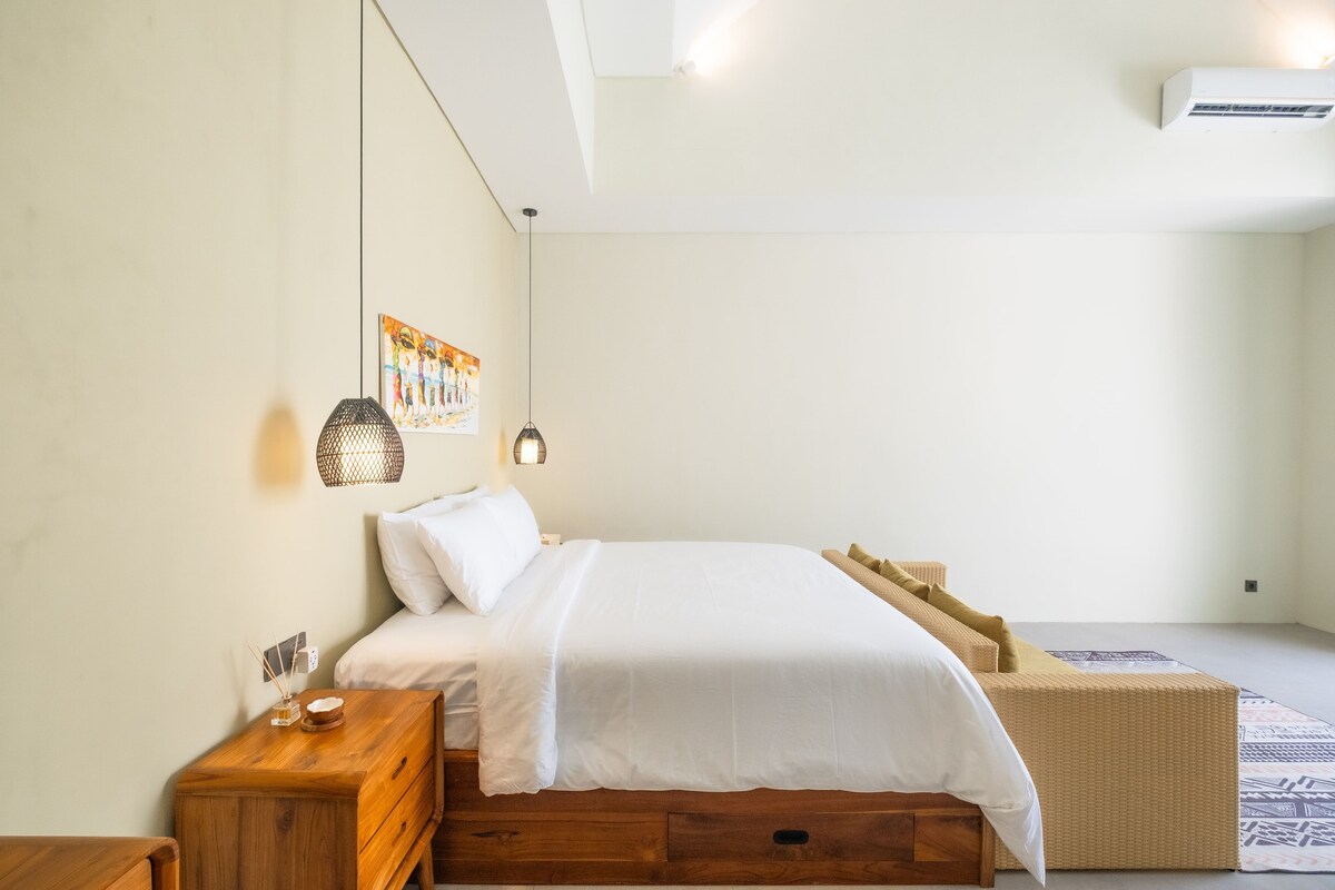 Dhomë gjumi e ndriçuar dhe e ajrosur me tavane të larta, me një krevat dopio "king" të rehatshëm, mobilje të ngrohta prej druri dhe tone të buta neutrale për një qëndrim relaksues.