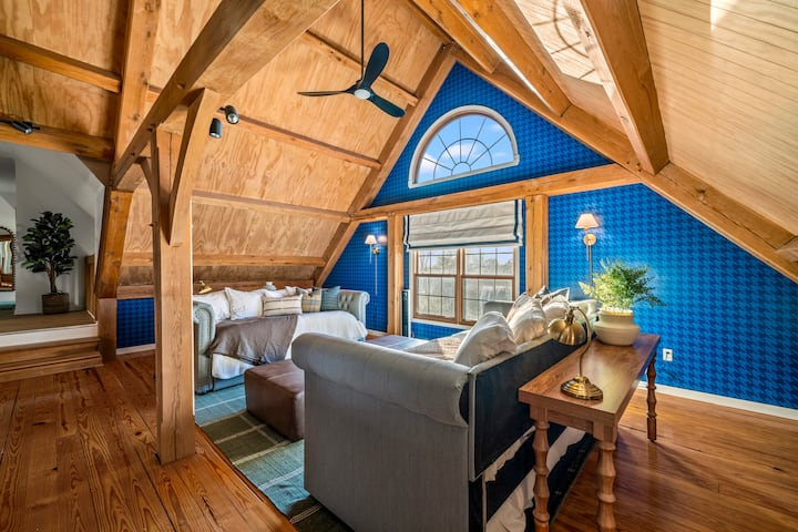 "Loft-style flexibility: This airy top floor combines rustic wood beams with bold blue patterned wallpaper. Two daybeds with trundles make this the perfect stylish retreat for extra guests. ✨