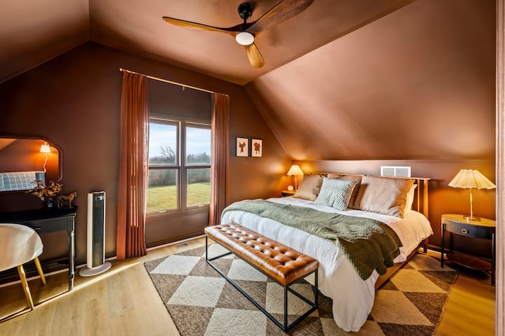 Serenity in every shade: Relax in this warm king suite, where dramatic slanted ceilings and rich earth tones meet peaceful countryside views—your private den for total rest.