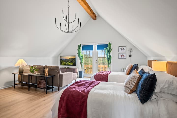 Your sun-drenched private retreat: This bright suite features cozy twin beds under vaulted ceilings and French doors that open directly to the deck—the perfect quiet corner for a peaceful morning coffee. ✨