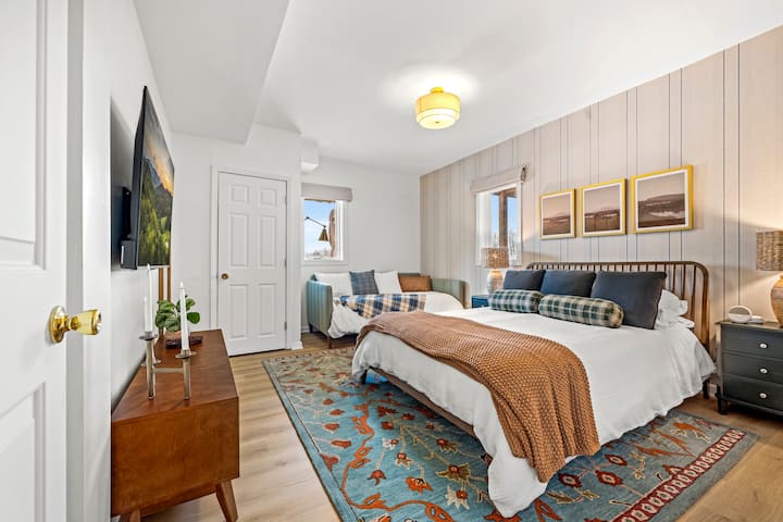 A curated corner for comfort: This stylish suite combines a plush queen bed with a versatile daybed, all set against elegant linear wallpaper—the perfect home base for your group's local adventures. ✨