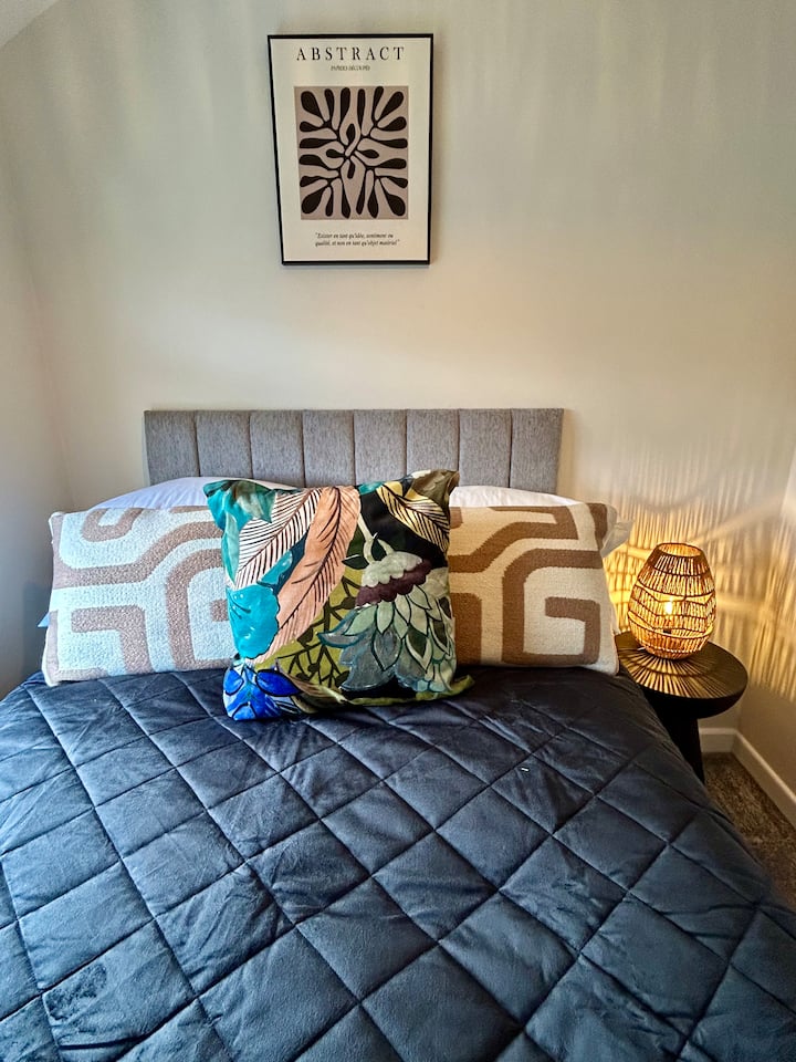 Двокреветна спална соба на првиот кат со поглед напред, со декор во неутрални меки црни тонови. Гардероба и стол. Поглед кон предната градина.