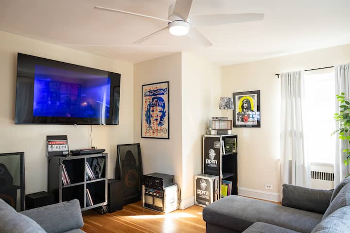 Luxurious, bright living room, 75" TV features custom content, curated record collection & turntable includes White Label Test Pressings, Fook, and other rarities, comfortable 7-seater couch, artwork from China Dub, Sheep on Drugs, & other projects.