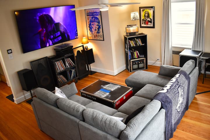 Luxurious, bright living room, 85" TV features custom content, curated record collection & turntable includes White Label Test Pressings, Fook, and other rarities, comfortable 7-seater couch, artwork from China Dub, Sheep on Drugs, & other projects.