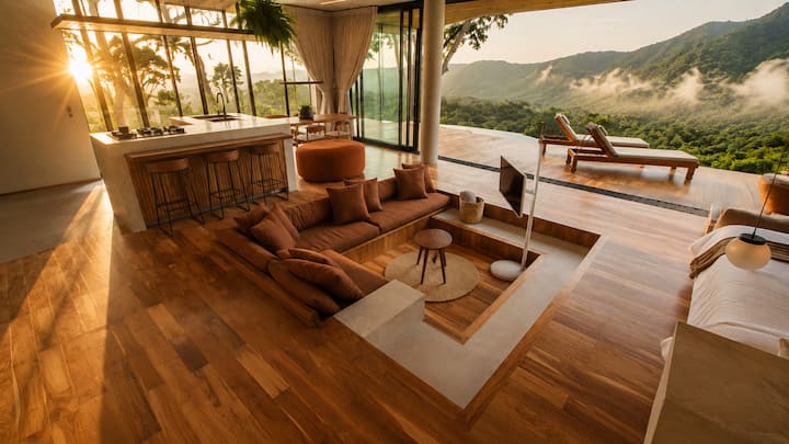 Sala rebaixada com sofá amplo, madeira e grandes aberturas para a natureza. Arquitetura contemporânea e design criam um ambiente acolhedor com vista para as montanhas.