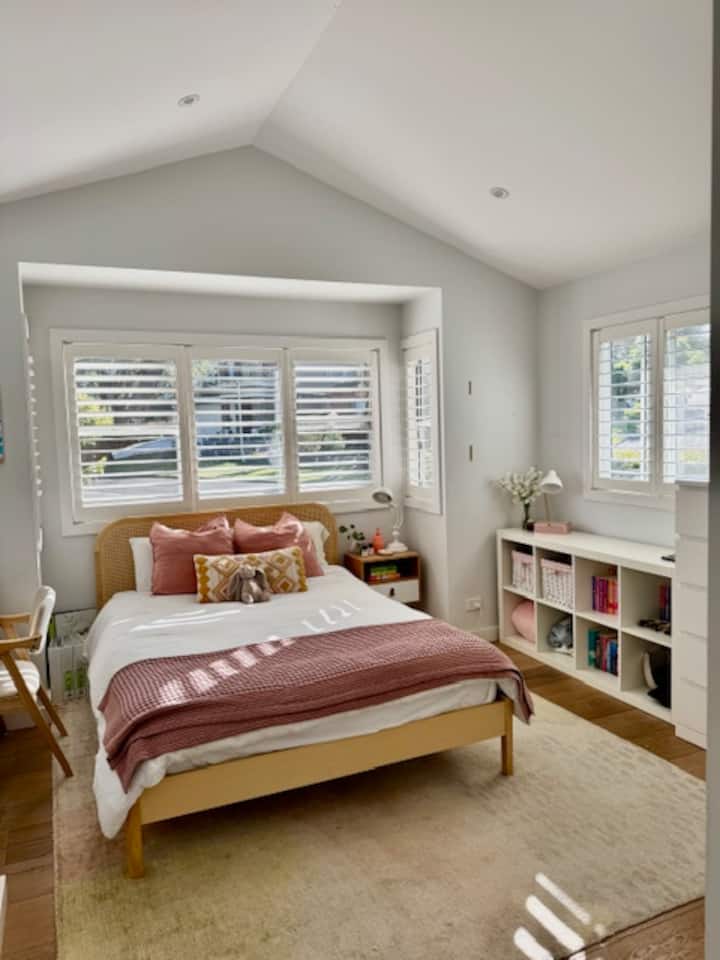 Светла спалня с двойно легло и много място за съхранение и бюро.