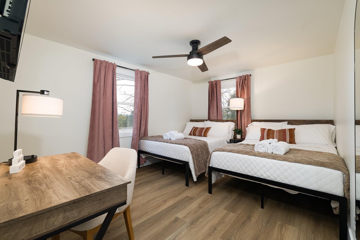 החדר הכפול כולל שתי מיטות בגודל מלא, טלוויזיה המותקנת על הקיר ושולחן נוח לעבודה מרחוק או למחשבה פרטית.