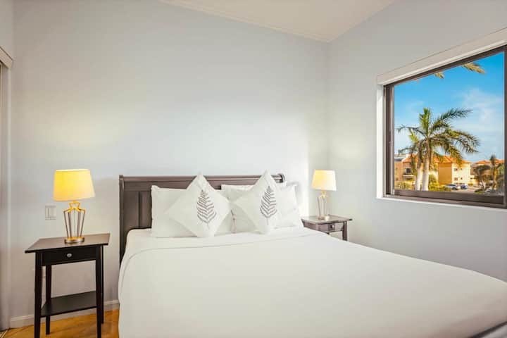 Svieža biela posteľná bielizeň a okná s palmami prinášajú do tohto svetlého a pokojného útočiska ostrovné čaro.