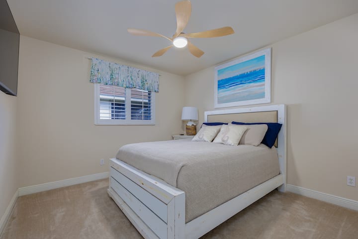 Hosťovská spálňa s nočným stolíkom, šatníkom, stropným ventilátorom s diaľkovým ovládaním a nástennou inteligentnou TV.