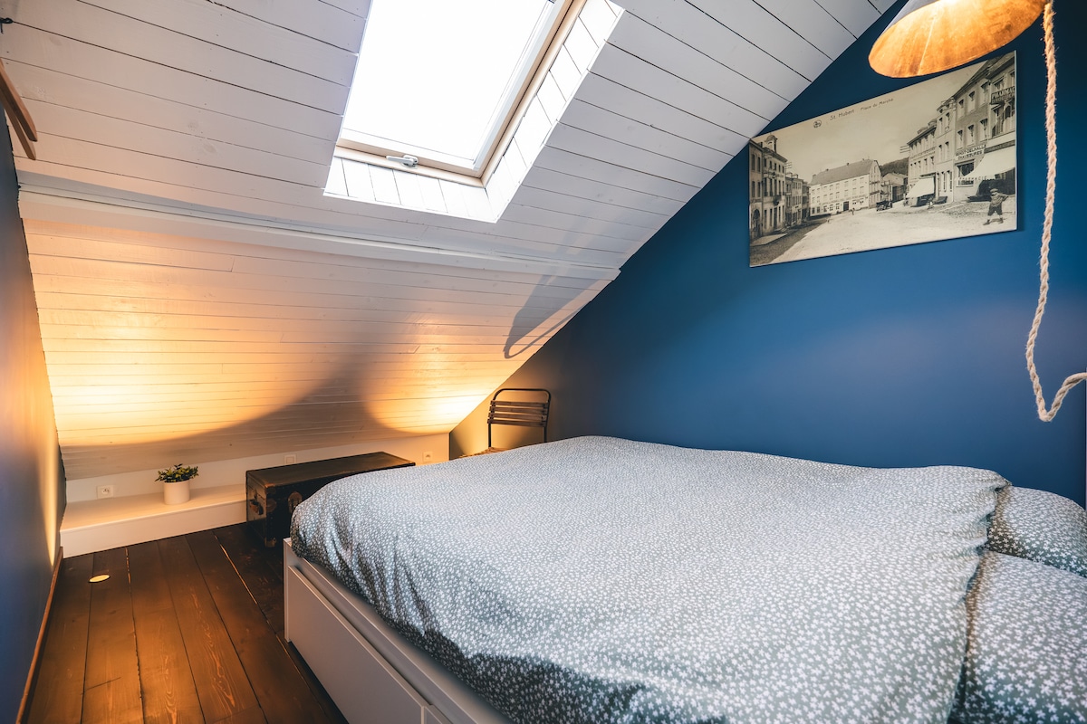 De lichte kamer heeft twee kapstokken, een stoel en decoratieve objecten die de authenticiteit van het huisje benadrukken.