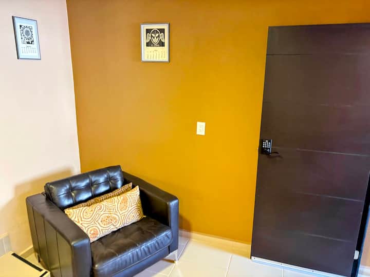 Moderný kútik s koženým kreslom, stenou vo farbe horčice a elegantným dekorom. Dvere s digitálnym zámkom a svetlý apartmán. Ideálne na oddych v pohodlnom, bezpečnom a štýlovom prostredí. Ideálne miesto na príjemný pobyt.