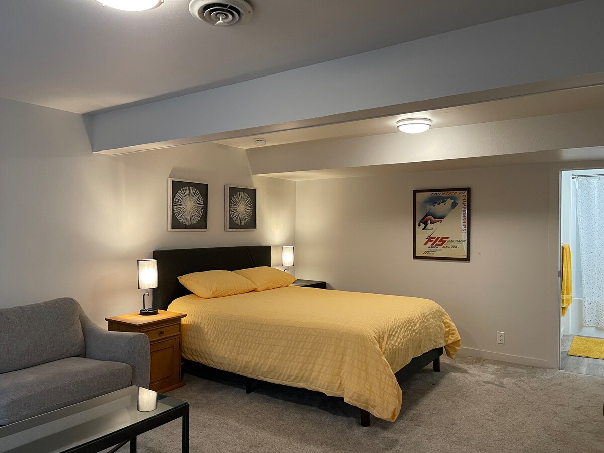 Dormitorio de nivel inferior con cama tamaño queen, iluminación suave y acceso directo al baño privado.