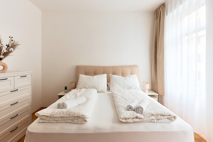 Elegantná spálňa s veľkou posteľou a čistou posteľnou bielizňou – čistý relax.
