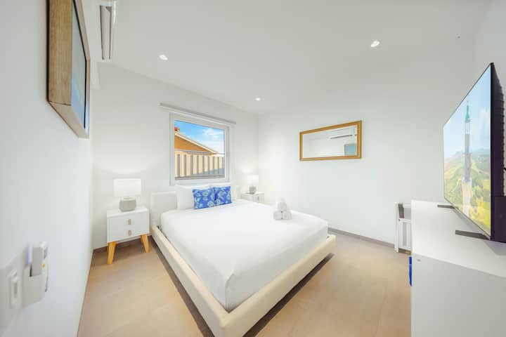 Quarto moderno com ar condicionado, smart TV e lençóis impecáveis — perfeito para relaxar após um dia de praia.