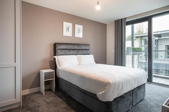 Rust gemakkelijk in een elegante slaapkamer met een kingsize bed met frisse witte lakens, comfortabele hoofdeinden, spiegelkasten en zachte gordijnen. Warme verlichting en een neutrale inrichting zorgen voor een rustige, stijlvolle retraite die perfect is voor rustgevende nachten tijdens je verblijf in Belfast.