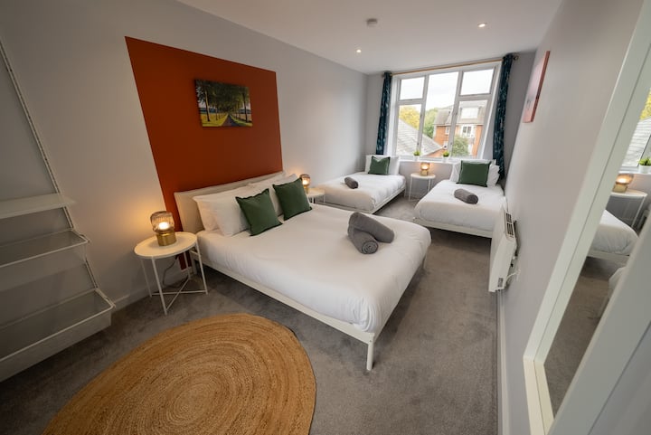 Spacious Long Family Bedroom with Extra throw pillows and art deco lamps. Bedroom has a double bed and two singles for the kids.