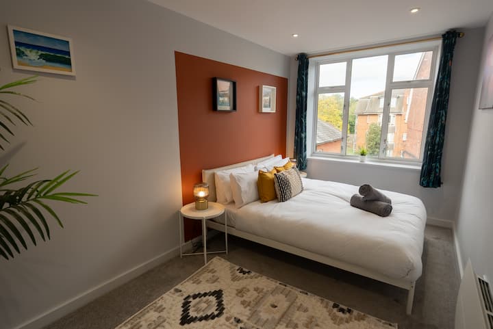 Spacious Master Bedroom with Extra throw pillows, art deco lamps & travel cot hidden under the bed.