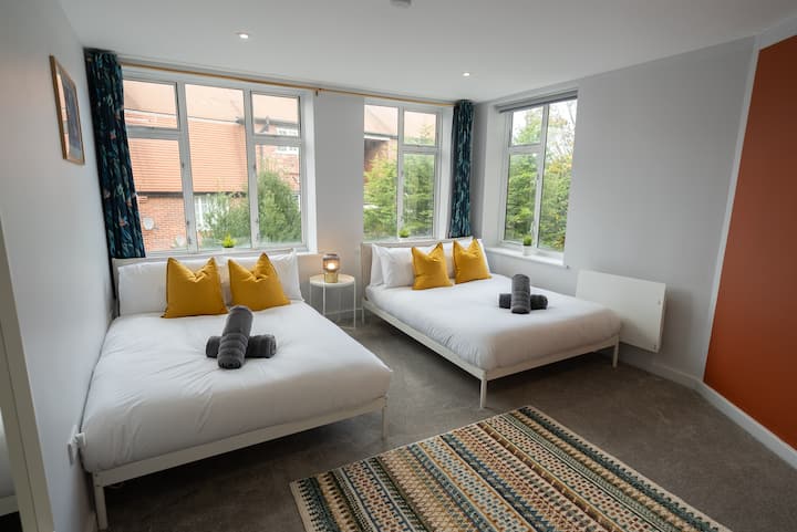 Large tastefully decorated bedroom with two double beds.