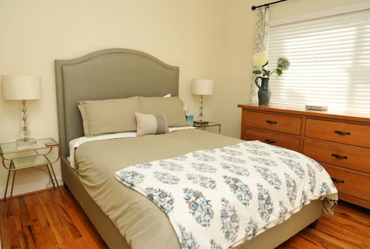 Un dormitorio secundario sereno con una lujosa cama tamaño queen, una decoración relajante y un baño privado adjunto. Un espacio tranquilo diseñado para la verdadera relajación.