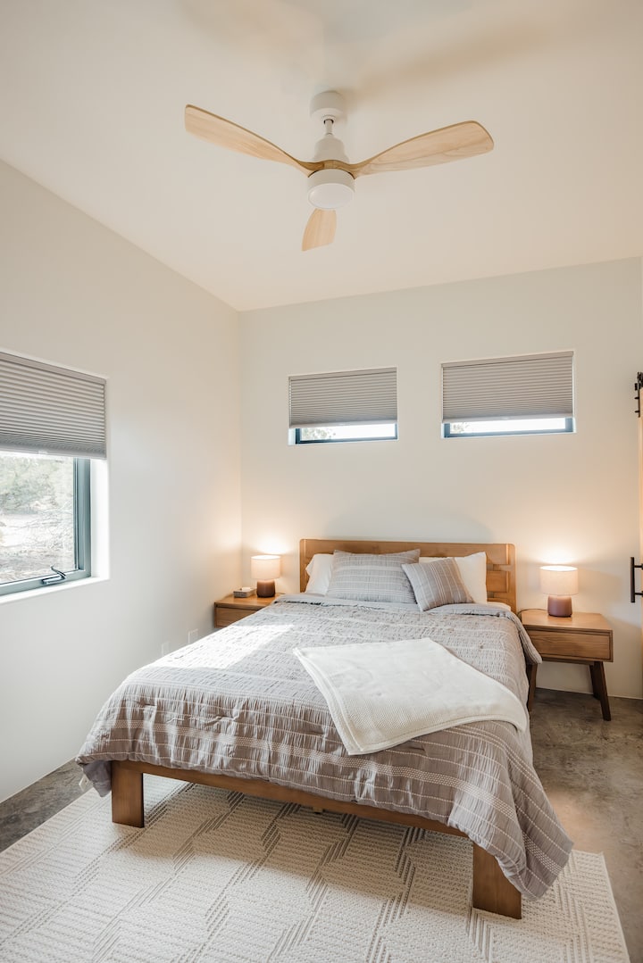 Second bedroom equipped with a queen bed, bedside tables, reading lights, and blackout cellular shares.