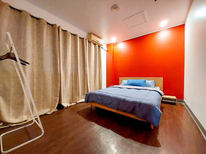 Bedroom includes a window for natural light, air conditioning for comfort, and a small hanger rack for your essentials (Queen Bed)