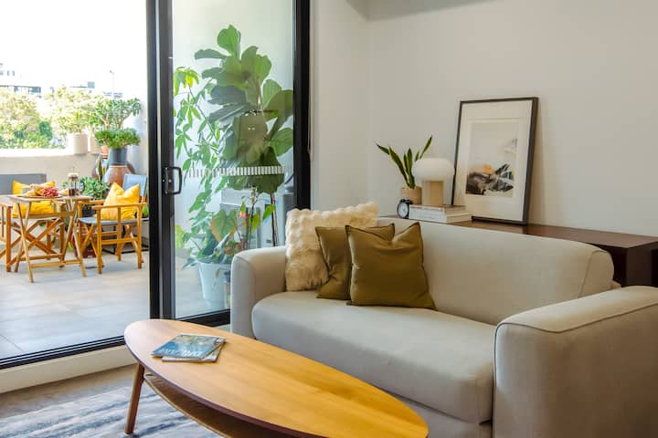 Salón lleno de luz con flujo continuo hacia el balcón privado, que combina la comodidad interior con la exuberante vegetación exterior. Abre las puertas corredizas para disfrutar del aire fresco y la luz natural durante todo el día.