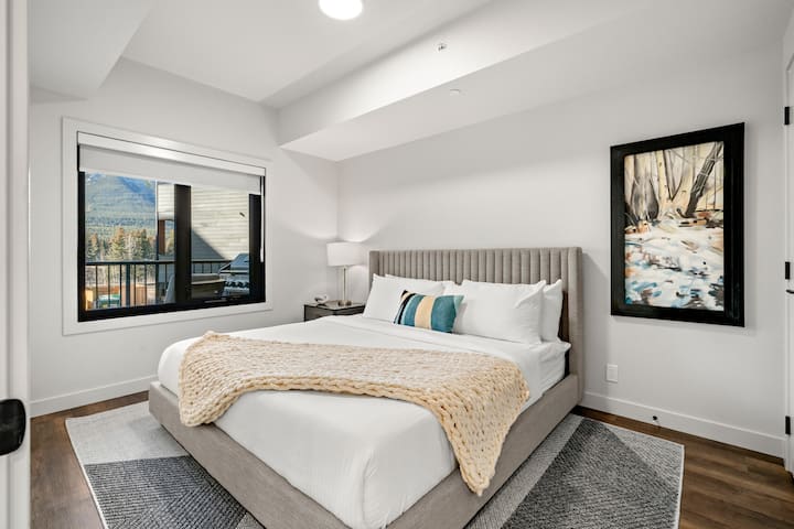 Chumba cha kulala cha pili chenye kitanda kikubwa chenye starehe, matandiko ya safu na mwonekano mzuri wa vilele vinavyozunguka.