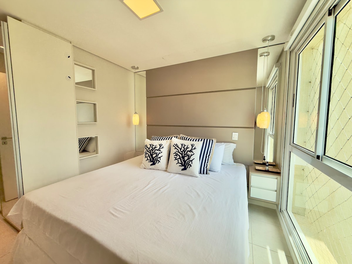 Suite parentale élégante avec lit taille king, trousseau blanc et oreillers décoratifs, tête de lit en bois et grandes fenêtres qui laissent entrer la lumière naturelle; détendez-vous et réveillez-vous en profitant de la vue sur la ville!