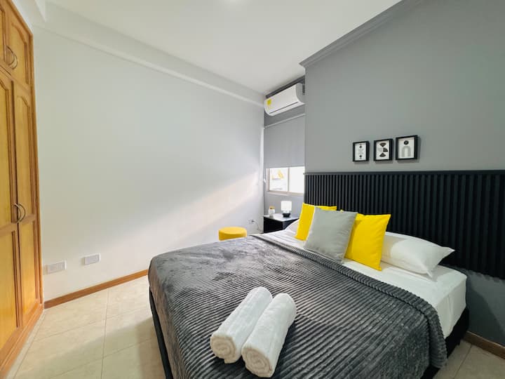 Este dormitorio cuenta con una cama cómoda, mesitas de noche modernas y un diseño de pared elegante, lo que proporciona un ambiente relajante y agradable.