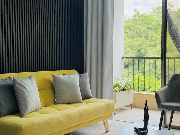 Bienvenido a esta acogedora sala de estar, con un cómodo sofá amarillo y una elegante mesa auxiliar, perfecta para relajarse y disfrutar de una noche tranquila.