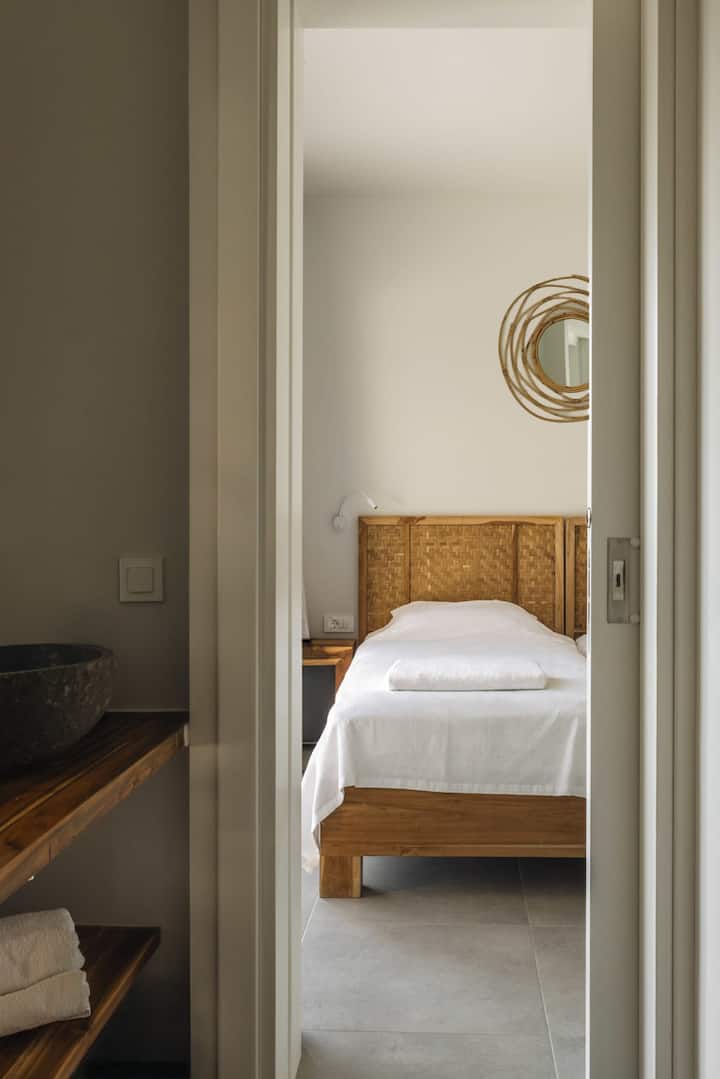 חדר שינה עם 2 מיטות יחיד וחדר הרחצה המשותף בין חדרי האורחים, עם כיור כפול ושירותים נפרדים