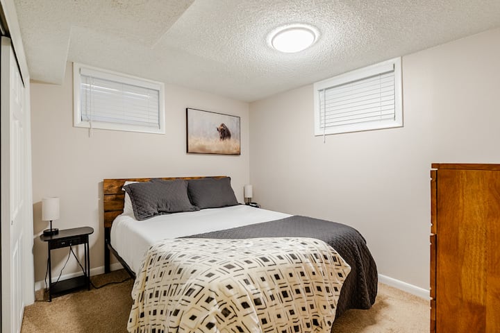 Dormitorio en el sótano con una acogedora cama tamaño queen, vestidor y armario amplios, con televisor para el entretenimiento. Se suministra con una máquina de sonido, un calentador de espacio y un ventilador de torre para mayor comodidad. 