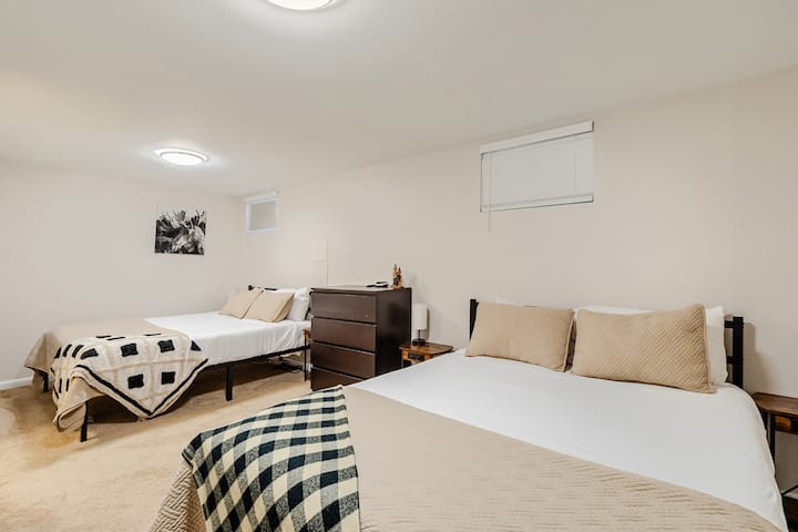 Dormitorio en el sótano con 2 cómodas camas tamaño queen y un espacio de trabajo designado. Se suministra con una máquina de sonido, un calentador de espacio y un ventilador de torre para mayor comodidad. 