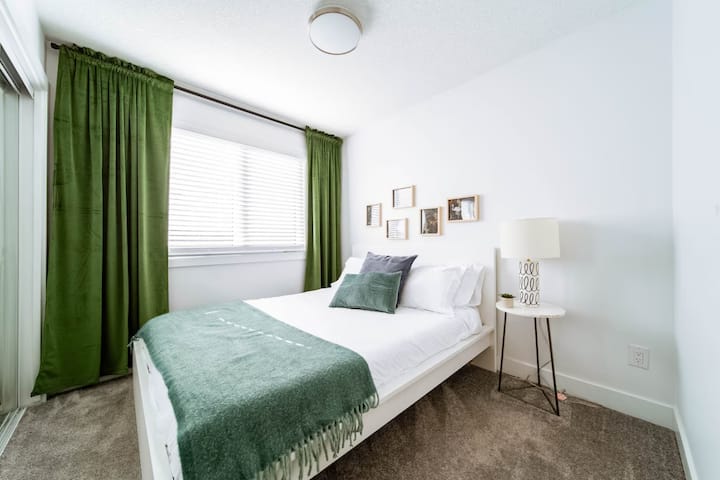 A second upstairs queen room with natural light, cozy bedding, and space to relax between family outings.