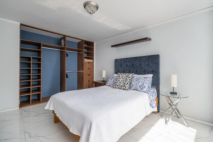 Habitación con cama queen y balcón privado. Su decoración sencilla y la luz natural crean un ambiente tranquilo, perfecto para descansar o disfrutar una lectura relajada al final del día.