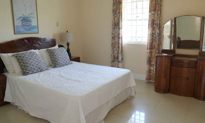 Deuxième chambre spacieuse à l'étage avec un lit king size et des meubles en acajou.