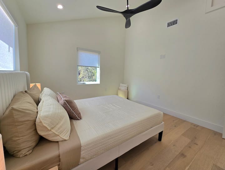 Amplio dormitorio con una cómoda cama tamaño queen vestida con sábanas frescas y de alta calidad