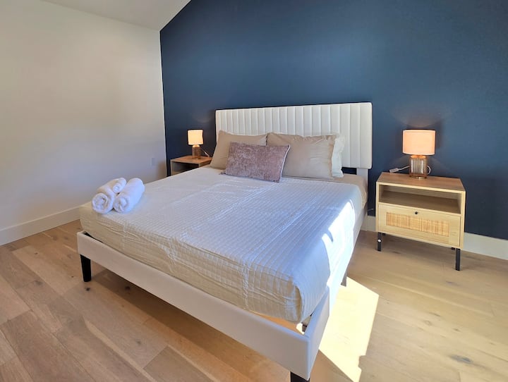 Amplio dormitorio con una cómoda cama tamaño queen vestida con sábanas frescas y de alta calidad.