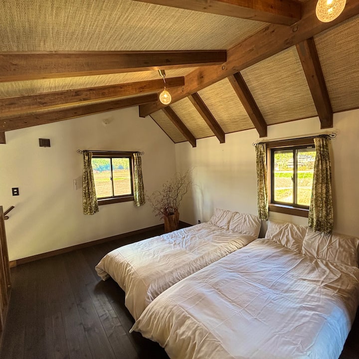 The bedroom upstairs is a bright space with soft natural light.
You can enjoy a peaceful morning surrounded by the warmth of the ceiling beams and wood.
The large windows overlook the rural landscape that changes with the seasons.