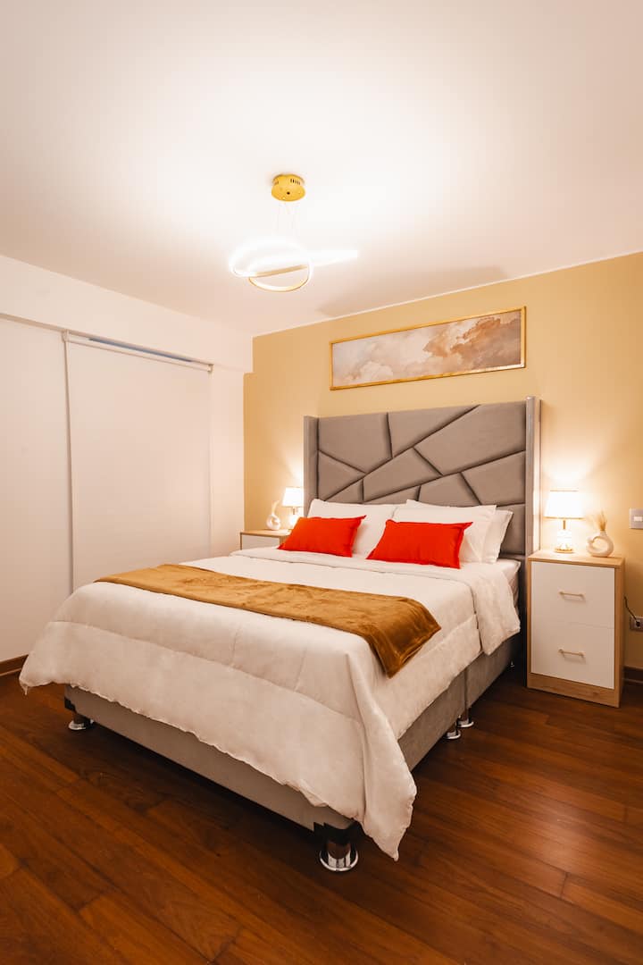 Главна спална соба со брачен кревет (широк 150 – 179 см), приватна бања и паметен телевизор. Нејзиниот геометриски потпирач за глава и топлите тонови покануваат на одмор, додека мекото осветлување и златните детали создаваат софистицирана и релаксирачка атмосфера за совршена ноќ.