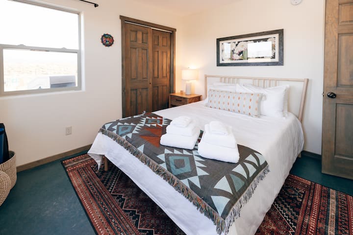 Second bedroom equipped with a queen bed, bedside table, reading light, and beautiful local art.