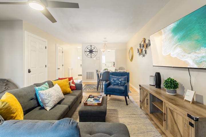 Svetlý a príjemný obývací priestor s otvorenou koncepciou, útulným sedením, dekoráciami inšpirovanými pobrežím a veľkou TV. Priestor prechádza do jedálne a kuchyne, čím vytvára ideálne miesto na oddych, stretávanie a spoločné trávenie času.