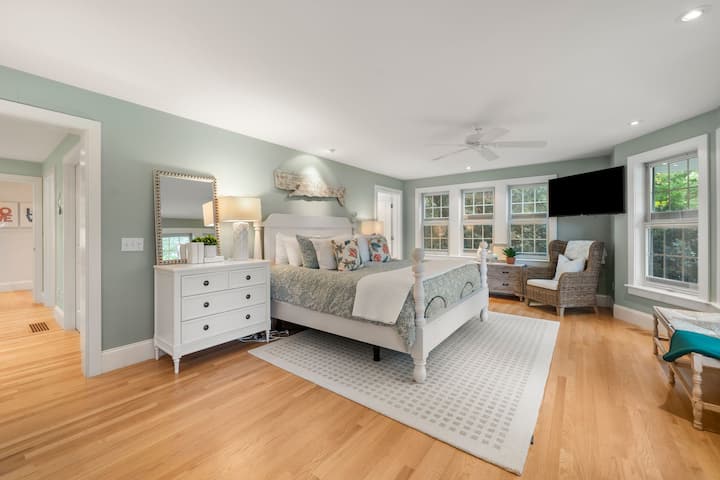 Primary bedroom with king bed, TV, dresser, ensuite bathroom, and walk-in closet & door direct to the patio.