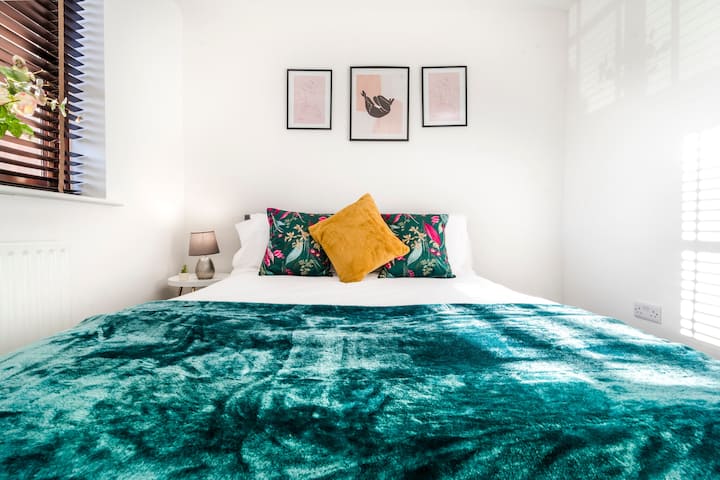 切姆斯福德宁静的睡眠天堂：豪华床铺，配有丰富的蓝绿色毯子、彩色花卉靠垫和金色装饰枕头。 三幅框架印花、柔和的照明、百叶窗—宁静、现代化和迷人。