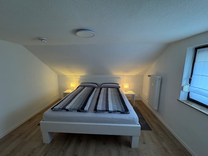 Cama de madera maciza de 180 x 200 cm con dos mesitas de noche y percheros.