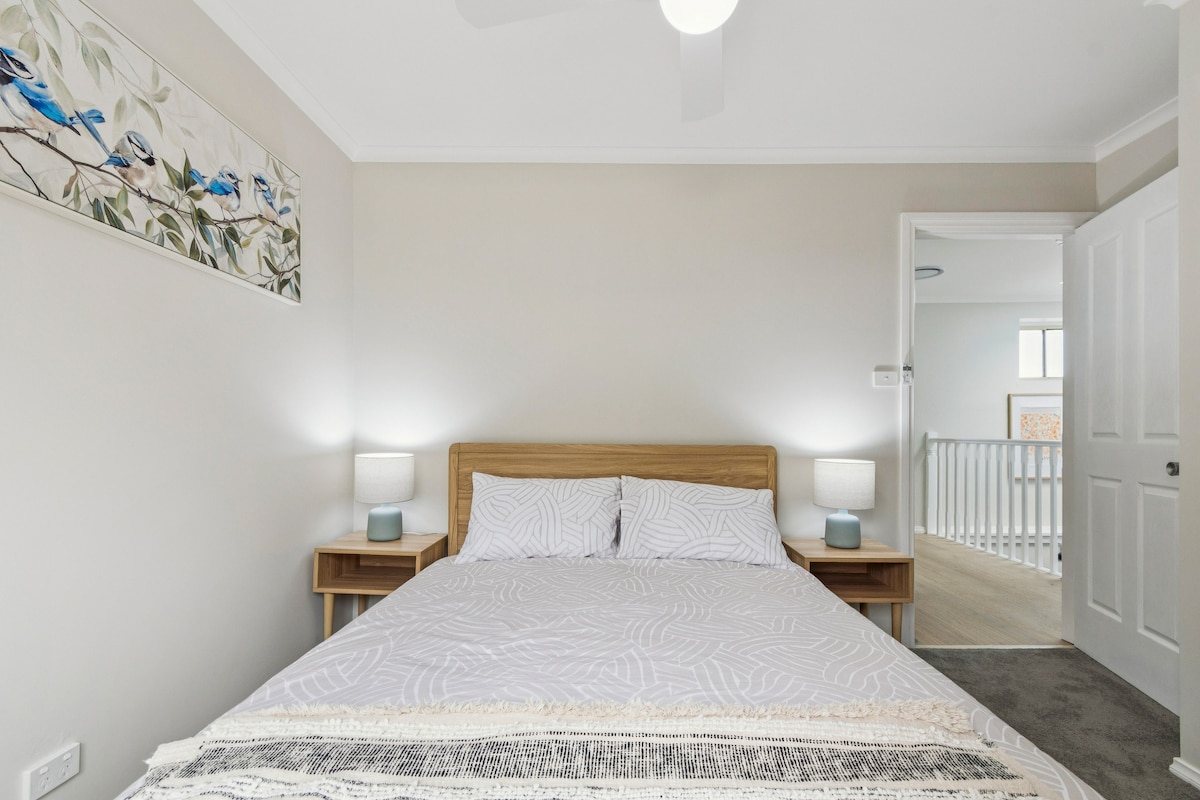 The third bedroom features a double bed dressed in crisp linens, soft lighting and direct access to a private balcony for quiet morning moments.